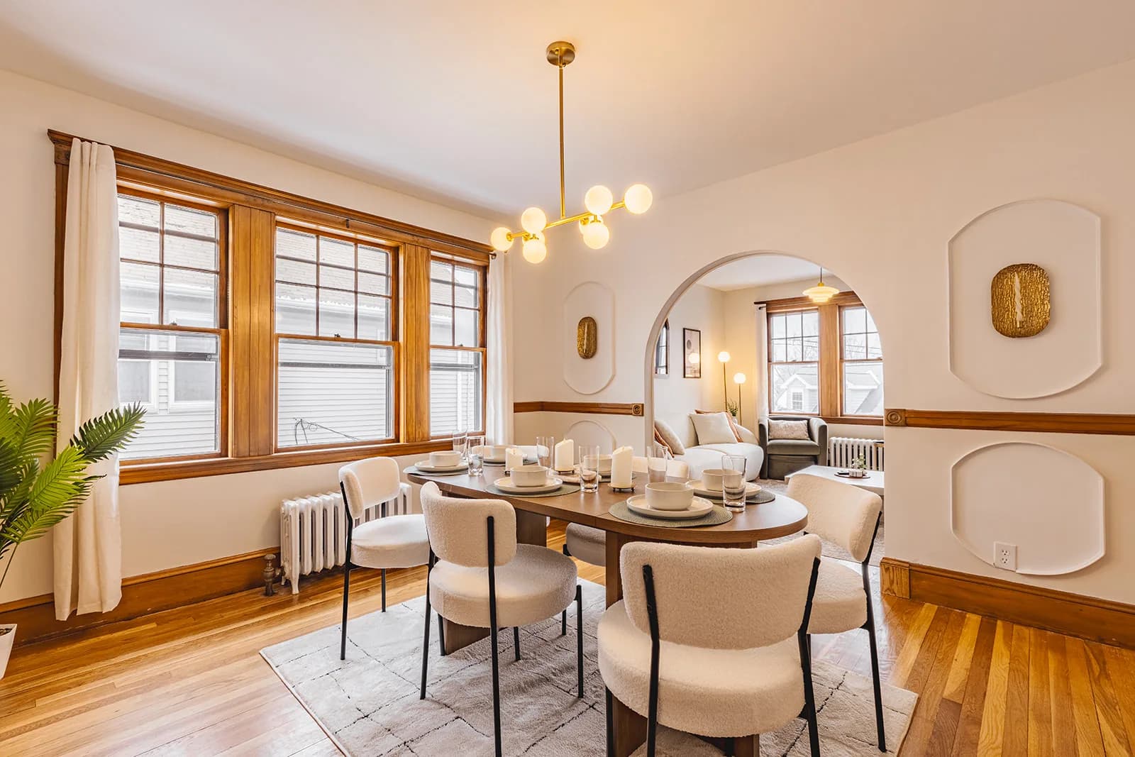 Furnished dining room with a round wood table, upholstered chairs, and warm pendant lighting, designed and furnished by R Living